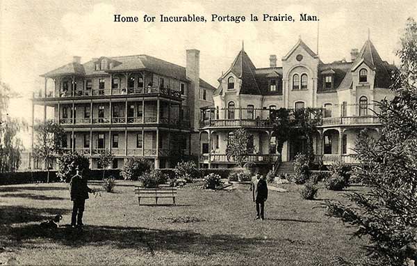 Postcard of the Home for Incurables with original building on the right and addition on the left. In the foreground is the front yard with two men and a dog. 