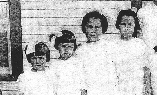 Four sisters standing side by side, wearing white dresses.
